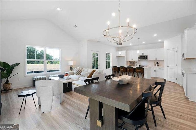 dining space featuring visible vents, recessed lighting, light wood-style flooring, a notable chandelier, and high vaulted ceiling