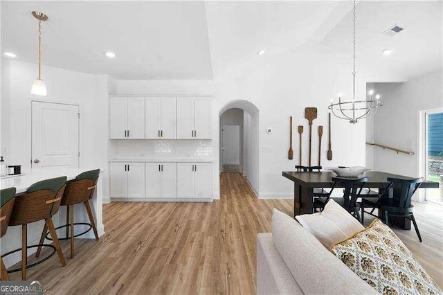 kitchen featuring arched walkways, light wood-style floors, white cabinets, and tasteful backsplash