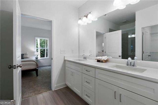 full bath with double vanity, wood finished floors, baseboards, and a sink