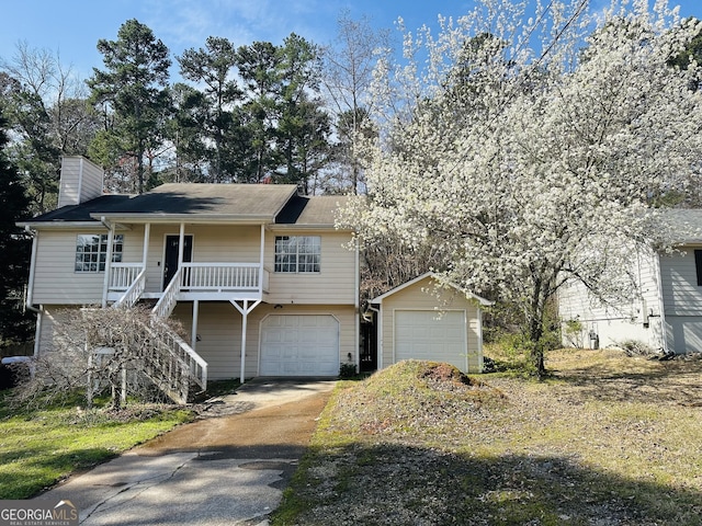 view of front of home with driveway, a porch, stairway, a garage, and a chimney