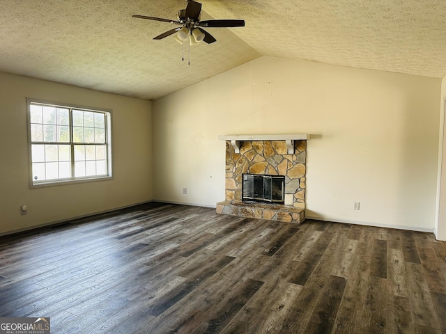 unfurnished living room featuring a ceiling fan, wood finished floors, a stone fireplace, vaulted ceiling, and a textured ceiling