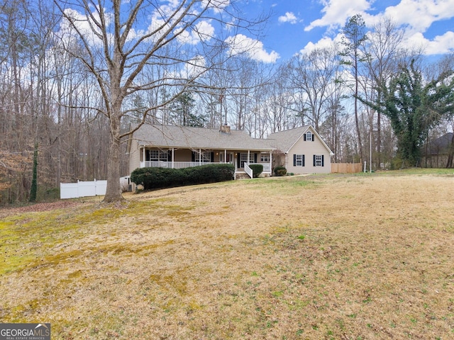 ranch-style house featuring a porch, a chimney, a front yard, and fence