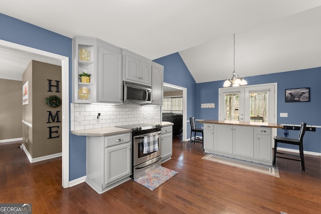 kitchen with a chandelier, dark wood finished floors, light countertops, lofted ceiling, and appliances with stainless steel finishes