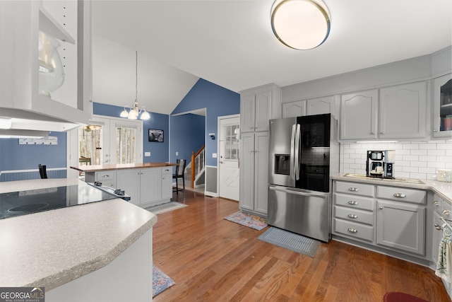 kitchen with french doors, stainless steel fridge, light countertops, black electric stovetop, and vaulted ceiling