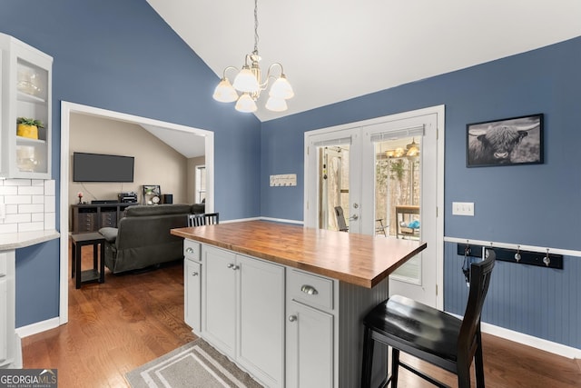 kitchen featuring dark wood finished floors, vaulted ceiling, an inviting chandelier, white cabinetry, and wood counters