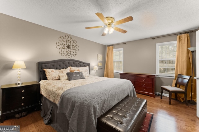 bedroom featuring multiple windows, a textured ceiling, and wood finished floors