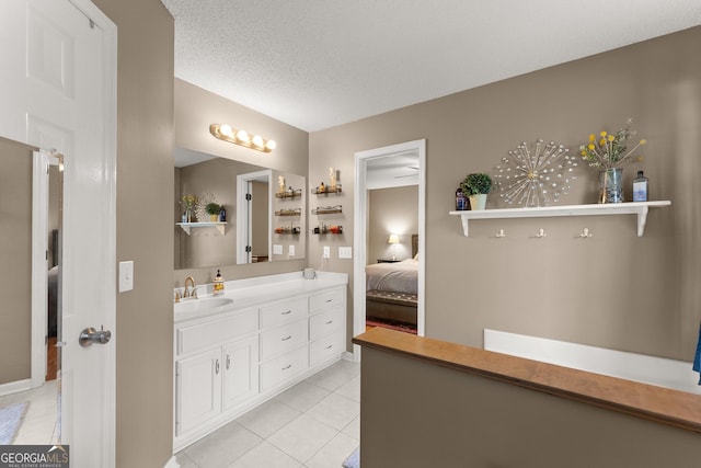 bathroom with tile patterned flooring, a textured ceiling, vanity, and ensuite bath