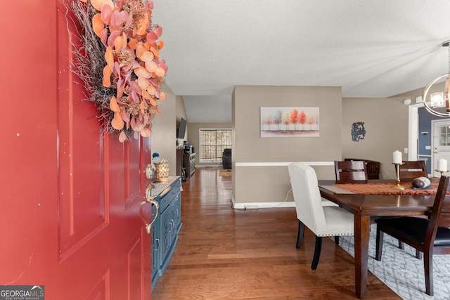 dining space featuring a notable chandelier, wood finished floors, baseboards, and a textured ceiling