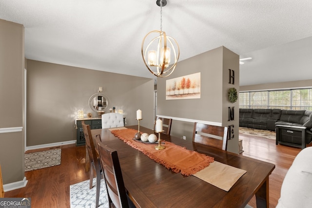 dining room with baseboards, wood finished floors, a textured ceiling, and a chandelier