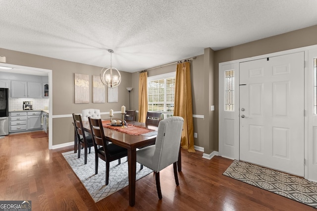 dining room with dark wood-type flooring, a notable chandelier, baseboards, and a textured ceiling