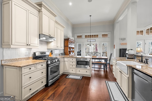 kitchen featuring ornamental molding, a sink, under cabinet range hood, stainless steel appliances, and a peninsula