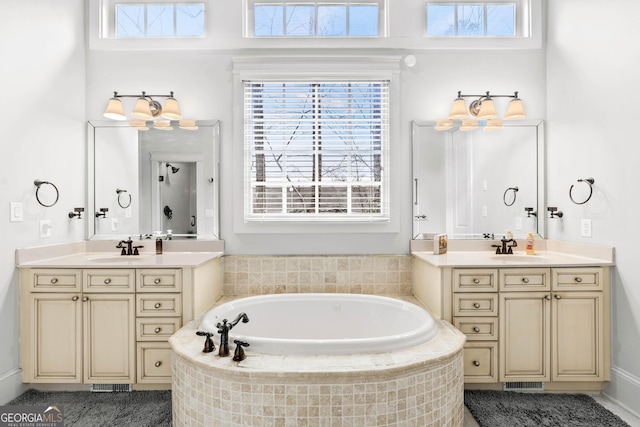 bathroom with two vanities, a garden tub, and a sink