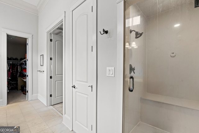 bathroom featuring a walk in closet, a shower stall, baseboards, and ornamental molding