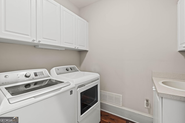 clothes washing area with visible vents, baseboards, separate washer and dryer, cabinet space, and a sink