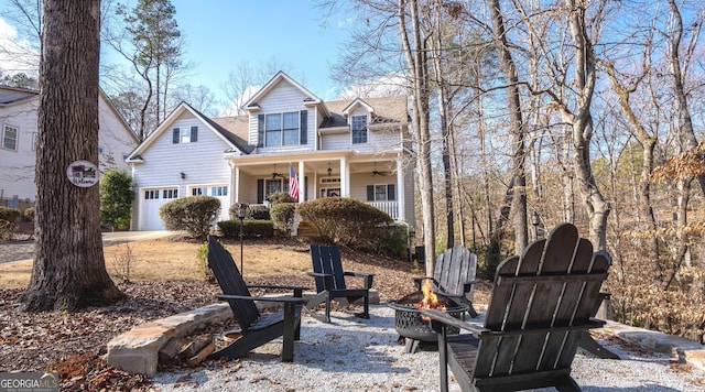 view of front of home with a porch, a fire pit, driveway, and ceiling fan