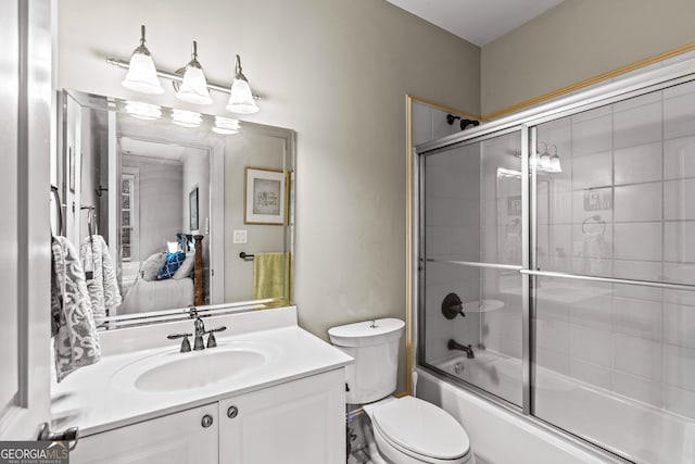 bathroom with toilet, vanity, and bath / shower combo with glass door