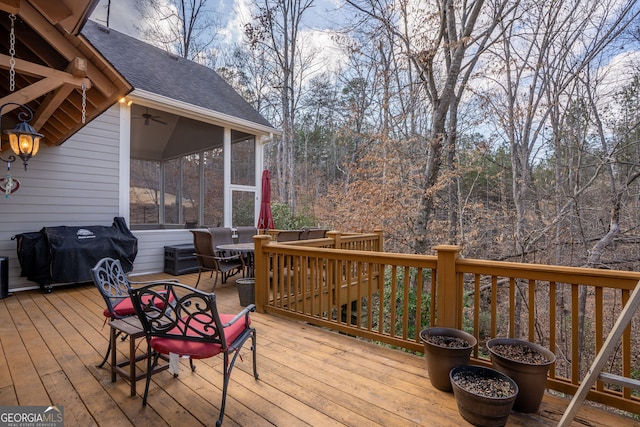 wooden deck featuring outdoor dining area, a sunroom, and a grill