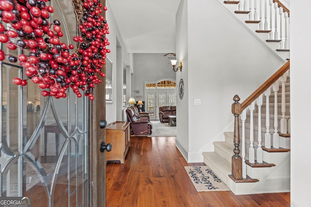 entryway with stairway, a high ceiling, baseboards, and hardwood / wood-style flooring