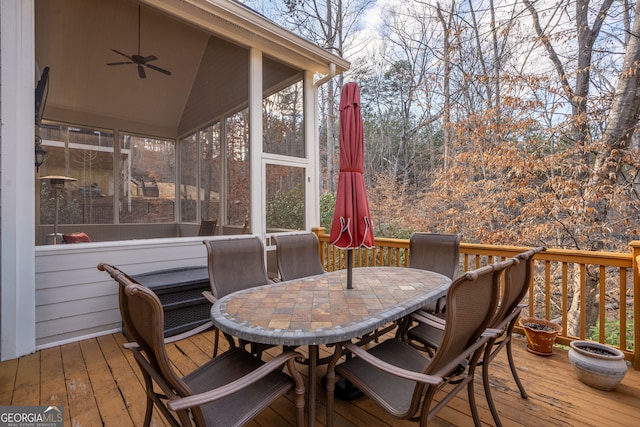 wooden deck featuring outdoor dining area, a ceiling fan, and a sunroom