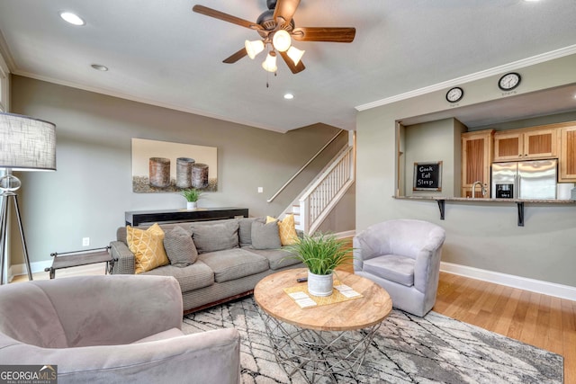 living area featuring stairs, crown molding, wood finished floors, and baseboards