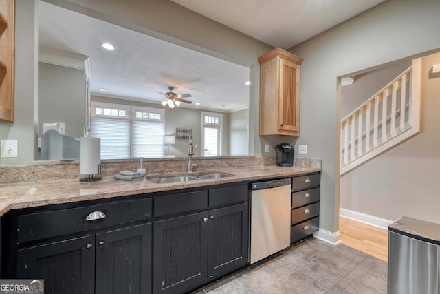 kitchen featuring a sink, light stone counters, baseboards, dishwasher, and ceiling fan