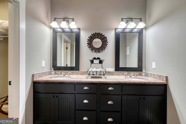 bathroom with double vanity, a spacious closet, and a sink