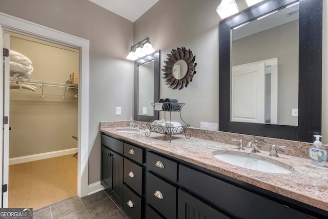 bathroom with a walk in closet, double vanity, tile patterned floors, and a sink