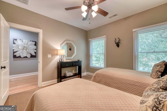 bedroom with visible vents, ceiling fan, baseboards, and wood finished floors