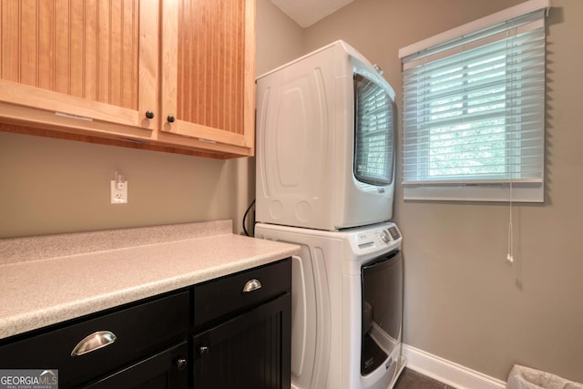 laundry room featuring baseboards, cabinet space, and stacked washer and clothes dryer