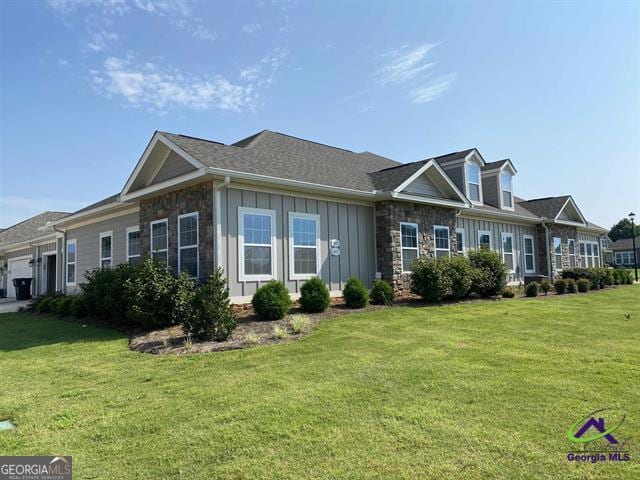 view of front of property with stone siding, board and batten siding, an attached garage, and a front yard