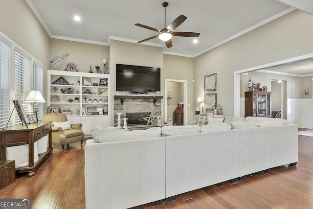 living area featuring wood finished floors, ceiling fan, and a fireplace