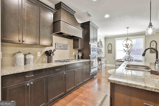 kitchen featuring backsplash, crown molding, appliances with stainless steel finishes, custom exhaust hood, and a sink