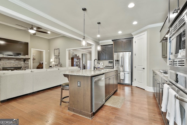 kitchen featuring a kitchen bar, open floor plan, appliances with stainless steel finishes, and a sink