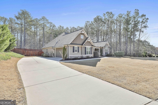 view of front of property with driveway, stone siding, fence, board and batten siding, and an attached garage