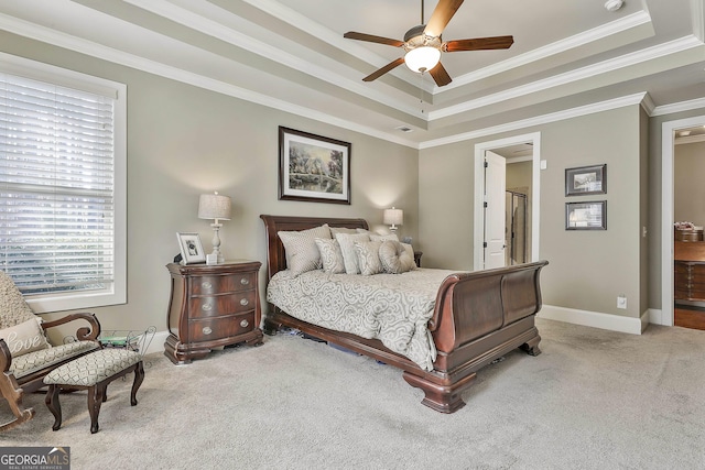 carpeted bedroom with a raised ceiling, baseboards, and ornamental molding