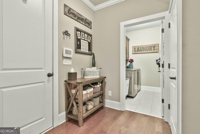 hallway with baseboards, wood finished floors, washing machine and dryer, and crown molding