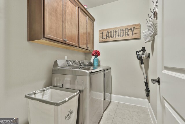 laundry area with washer and clothes dryer, cabinet space, baseboards, and light tile patterned flooring