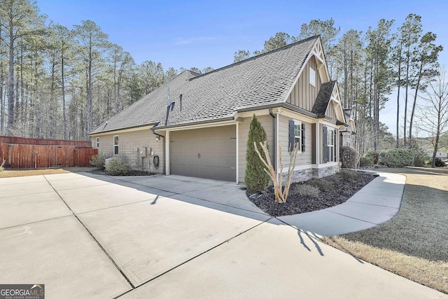 view of side of property with fence, board and batten siding, roof with shingles, concrete driveway, and an attached garage