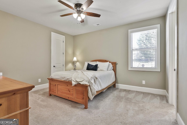 bedroom featuring visible vents, light colored carpet, a ceiling fan, and baseboards