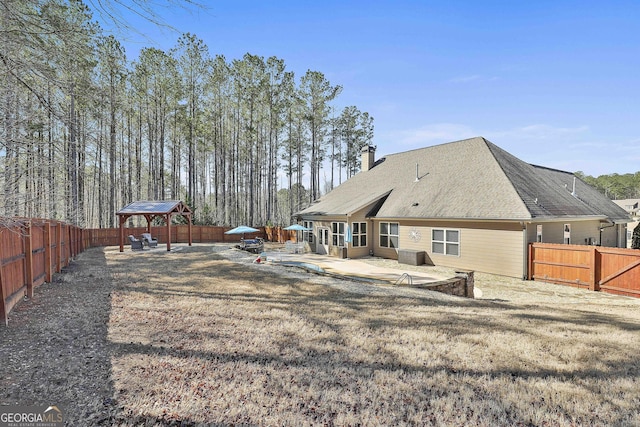 back of house with a gazebo, a patio area, a fenced backyard, and a chimney