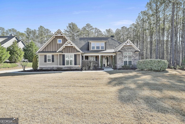 craftsman inspired home featuring stone siding, board and batten siding, a shingled roof, and a front yard