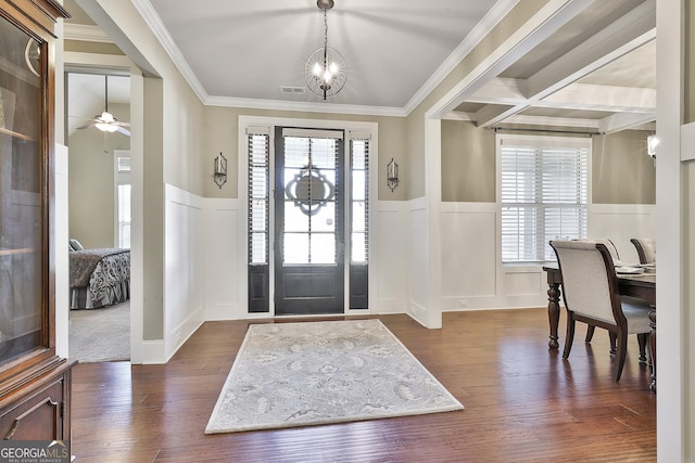 foyer entrance with a wainscoted wall, crown molding, dark wood-style flooring, and a decorative wall