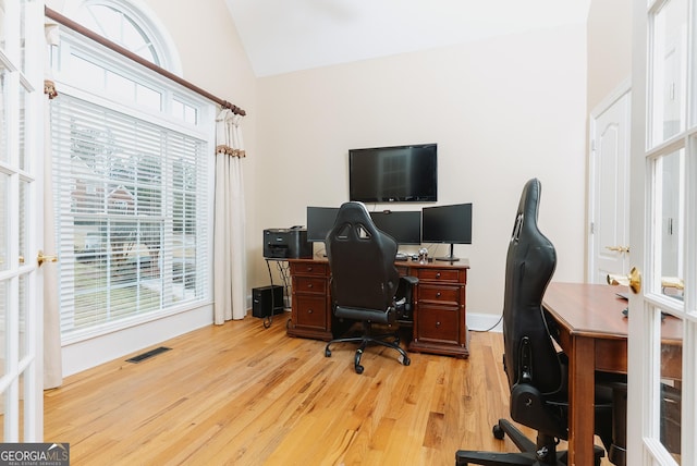 office space featuring visible vents, lofted ceiling, and light wood-style floors