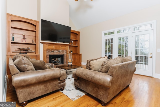 living room with light wood-style flooring, a brick fireplace, high vaulted ceiling, and baseboards