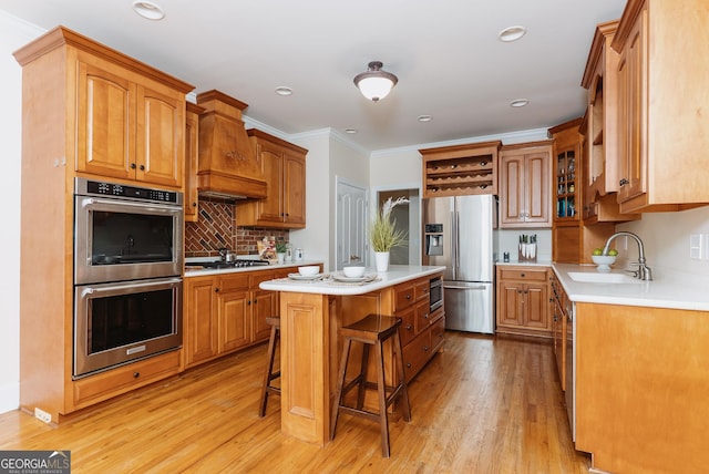 kitchen with a center island, premium range hood, a breakfast bar area, stainless steel appliances, and a sink