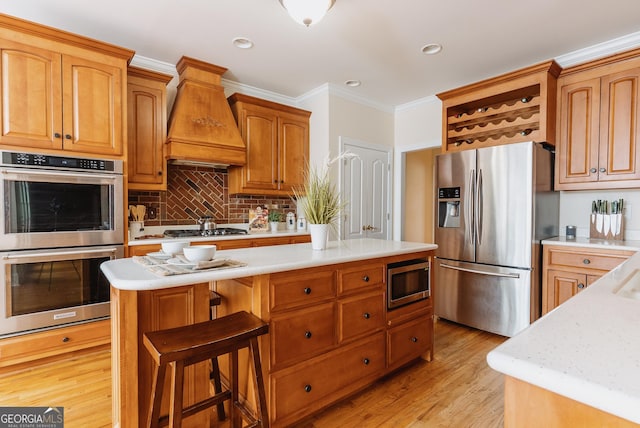 kitchen with light wood finished floors, appliances with stainless steel finishes, light countertops, and premium range hood