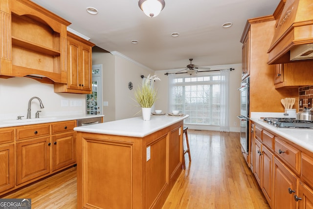 kitchen featuring light wood-type flooring, a center island, appliances with stainless steel finishes, light countertops, and ceiling fan