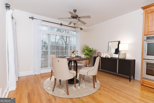 dining area featuring light wood finished floors, baseboards, crown molding, and a ceiling fan