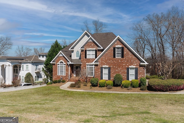 view of front facade featuring brick siding, a shingled roof, and a front lawn