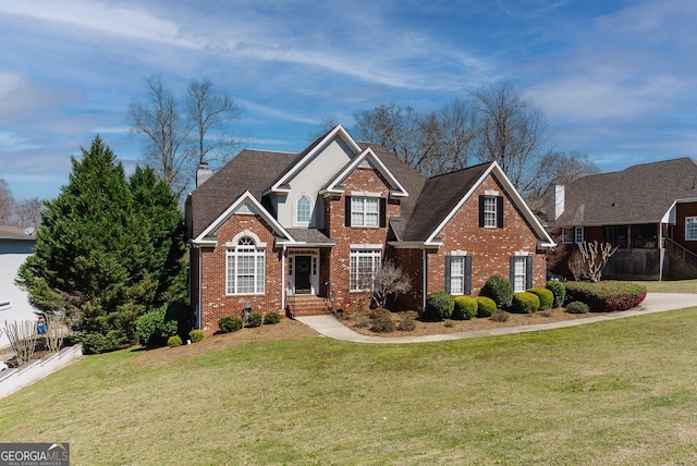 traditional-style house featuring a front lawn, fence, brick siding, and roof with shingles
